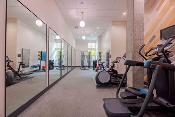 A gym with treadmills, exercise bikes, and mirrors.